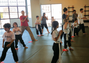 kids and parents' martial arts classes working on focus listening to instructions