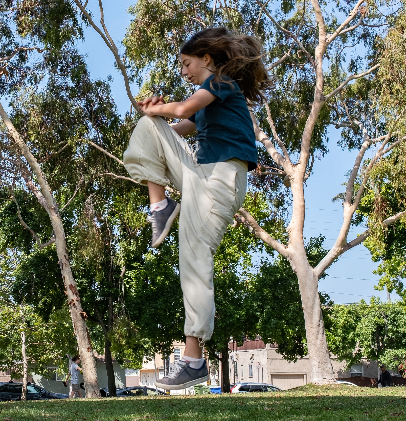 girl doing flying knee kick outside at a park